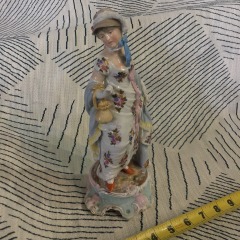 antique porcelain figurine of a woman Part of the bow is missing and chipped pinky