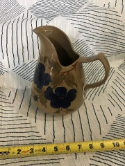 Handcrafted ceramic pitcher features a glossy brown glaze