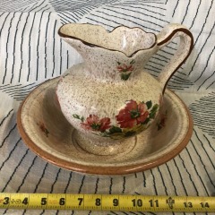 Vintage pottery pitcher and wash basin set featuring a beige speckled glaze with a red floral design