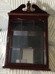 vintage solid wood curio cabinet features a decorative pediment top and a mirrored back interior.